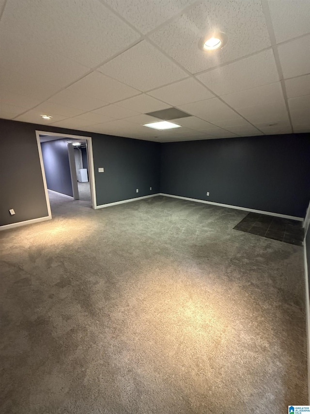carpeted spare room with baseboards and a drop ceiling
