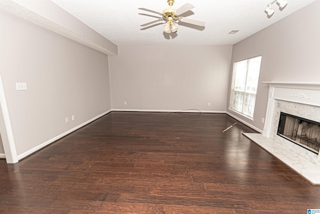 unfurnished living room with a textured ceiling, a ceiling fan, baseboards, wood finished floors, and a high end fireplace