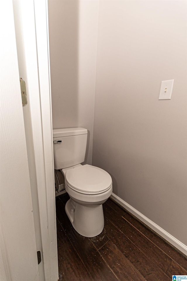bathroom with wood-type flooring, toilet, and baseboards