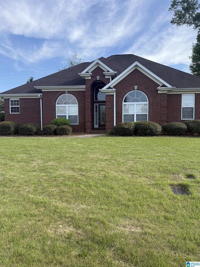 ranch-style home featuring a front yard and brick siding