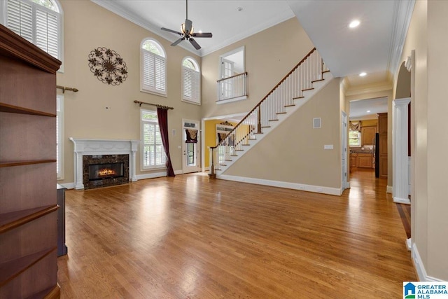 1065 Saint Andrews Pkwy, Oneonta, AL 35121 - unfurnished living room featuring a high end fireplace, ceiling fan, light wood-style flooring, baseboards, and ornamental molding