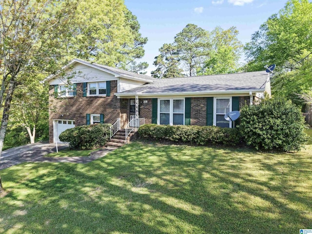 split level home with an attached garage, aphalt driveway, a front yard, and brick siding