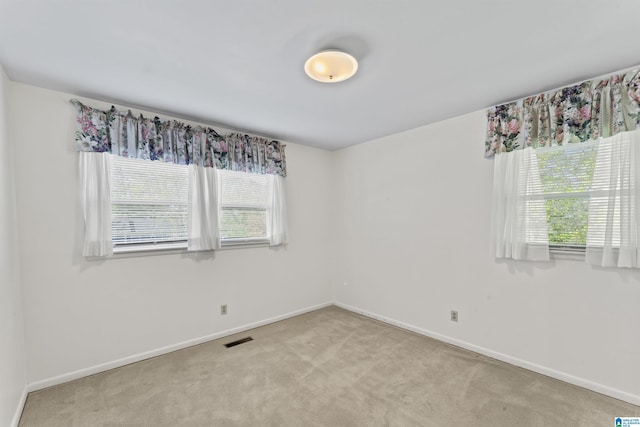 carpeted empty room featuring baseboards and visible vents