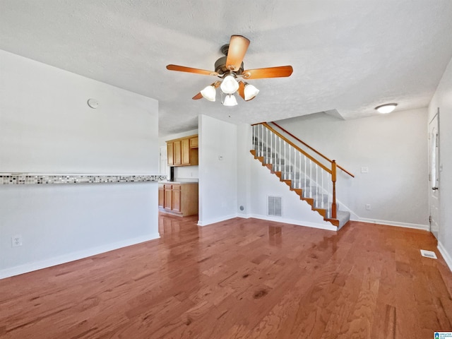 3 Holt Ave, Birmingham, AL 35214 - unfurnished living room featuring visible vents, baseboards, ceiling fan, stairs, and light wood-style flooring