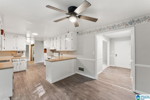 kitchen featuring white electric range, white cabinetry, backsplash, ceiling fan, and under cabinet range hood
