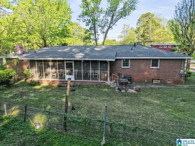 rear view of property featuring brick siding, a sunroom, a shingled roof, and fence