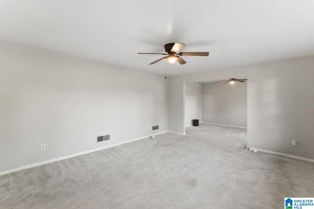 carpeted spare room with baseboards, a ceiling fan, and visible vents