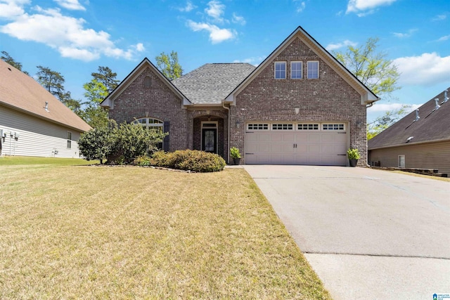 view of front of house with concrete driveway, roof with shingles, an attached garage, a front lawn, and brick siding