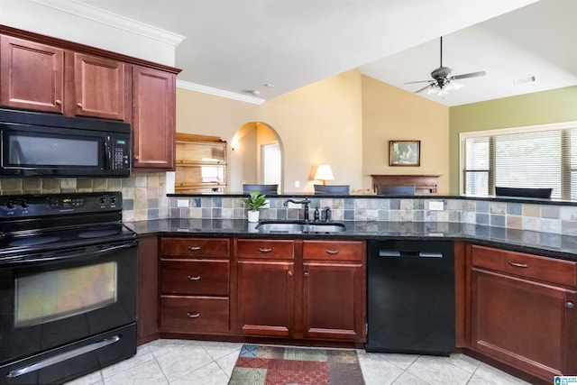 kitchen featuring tasteful backsplash, dark stone countertops, a sink, reddish brown cabinets, and black appliances