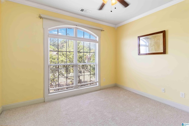 spare room with crown molding, a ceiling fan, visible vents, carpet floors, and baseboards