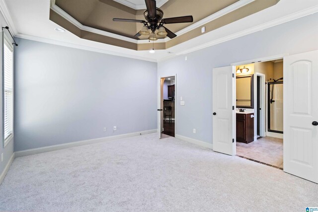 unfurnished bedroom featuring ornamental molding, baseboards, a tray ceiling, and light carpet