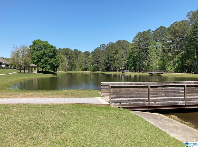 view of property's community with a water view, a gazebo, a wooded view, and a yard