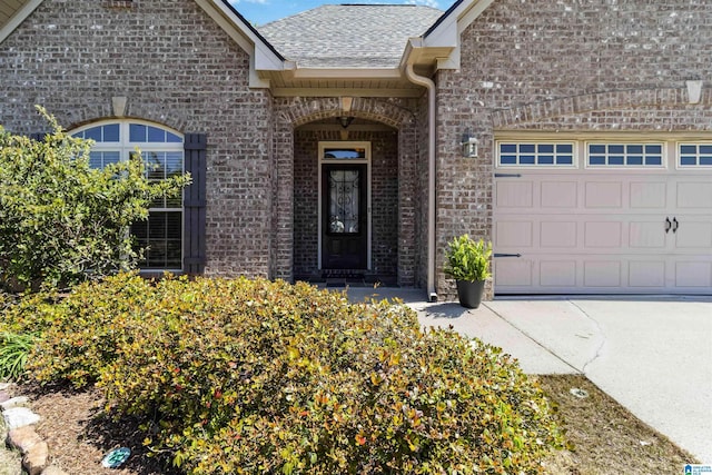 entrance to property featuring brick siding, an attached garage, and a shingled roof