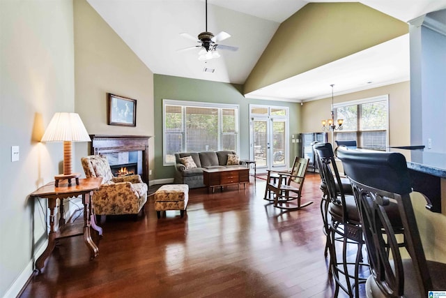 living area with baseboards, dark wood-style flooring, vaulted ceiling, ceiling fan with notable chandelier, and a premium fireplace