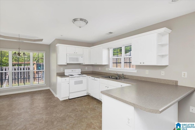 kitchen with visible vents, a sink, a wealth of natural light, white appliances, and a peninsula