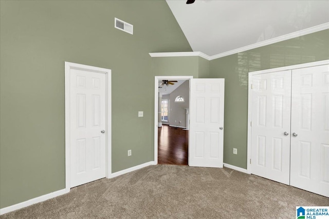 unfurnished bedroom featuring visible vents, baseboards, ornamental molding, carpet, and high vaulted ceiling