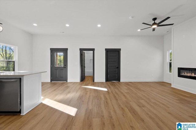 400 Ingram Ave W, Oneonta, AL 35121 - unfurnished living room featuring a ceiling fan, light wood finished floors, a glass covered fireplace, and a healthy amount of sunlight