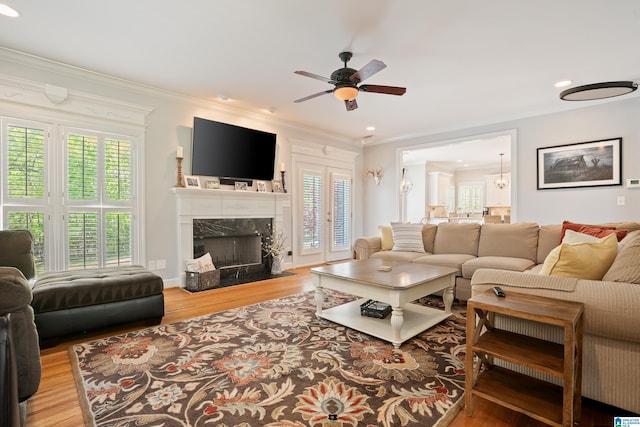 living area with ornamental molding, a ceiling fan, wood finished floors, and a high end fireplace