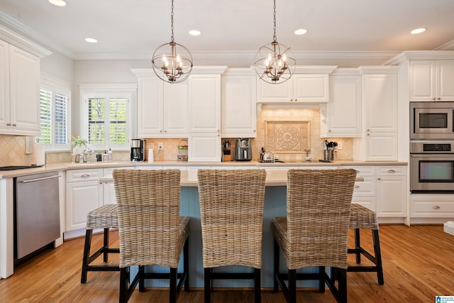 kitchen featuring a breakfast bar, stainless steel appliances, light wood finished floors, light countertops, and white cabinets
