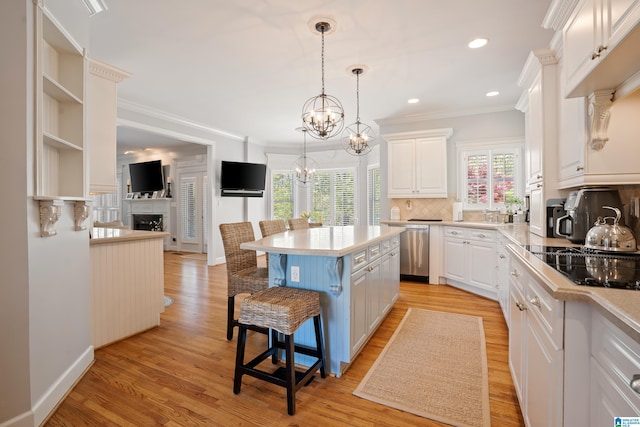 kitchen featuring a breakfast bar, light countertops, stainless steel dishwasher, and white cabinetry