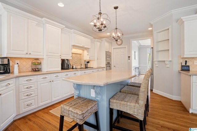 kitchen with backsplash, a chandelier, light countertops, a breakfast bar, and appliances with stainless steel finishes