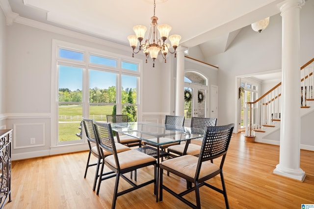 dining area featuring light wood-type flooring, an inviting chandelier, stairway, and crown molding