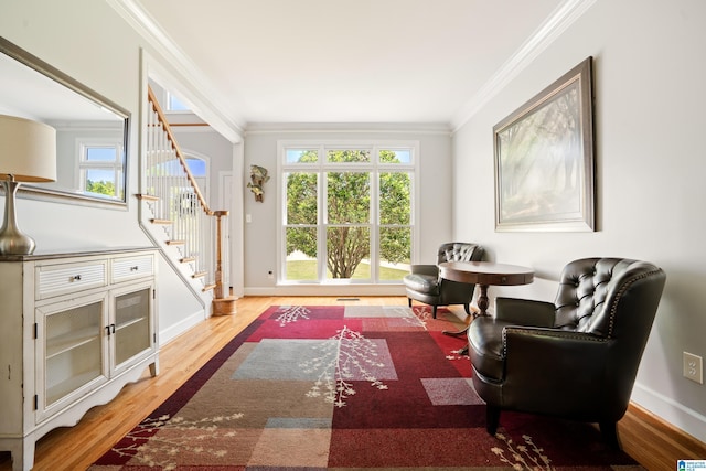 sitting room featuring baseboards, wood finished floors, crown molding, and stairs
