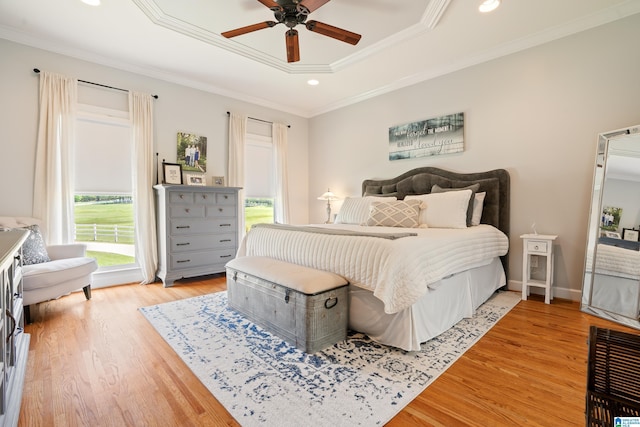 bedroom featuring light wood-type flooring, recessed lighting, a raised ceiling, and crown molding