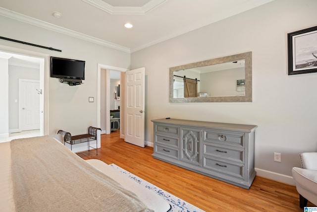 bedroom featuring a barn door, baseboards, ornamental molding, and light wood-style floors