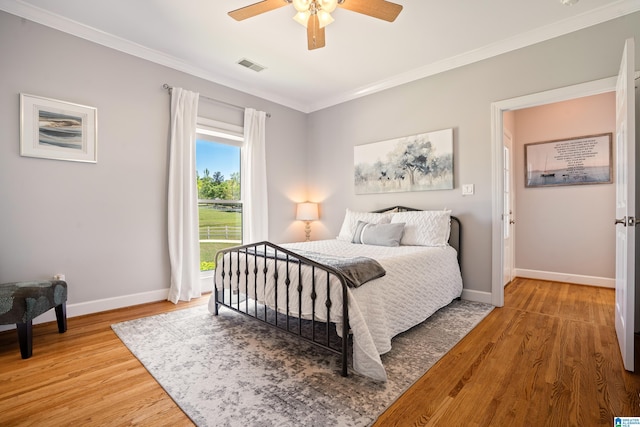 bedroom with baseboards, ornamental molding, light wood-style floors, and visible vents