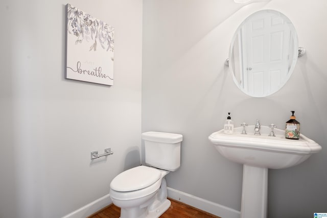 bathroom with baseboards, toilet, and wood finished floors