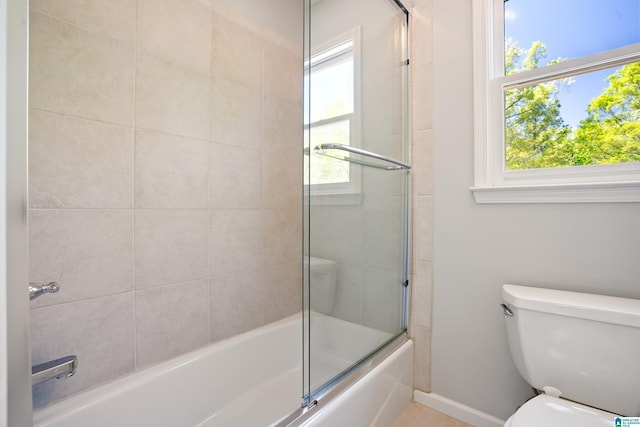 bathroom with combined bath / shower with glass door, toilet, and baseboards
