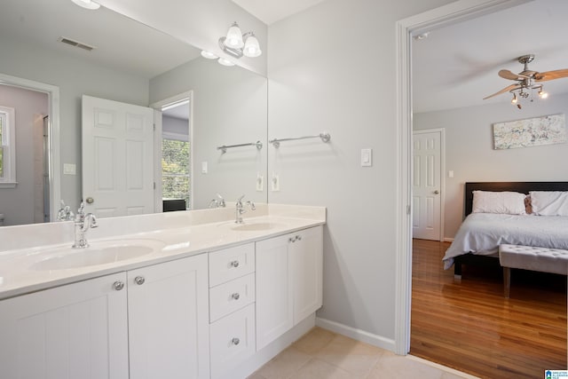 ensuite bathroom with visible vents, baseboards, ceiling fan, and a sink
