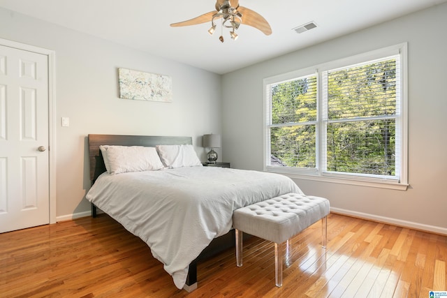 bedroom with light wood-type flooring, visible vents, a ceiling fan, and baseboards