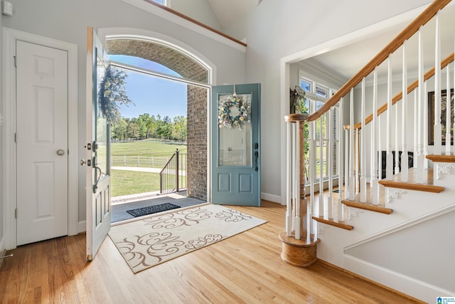foyer entrance featuring wood finished floors, lofted ceiling, baseboards, and stairway