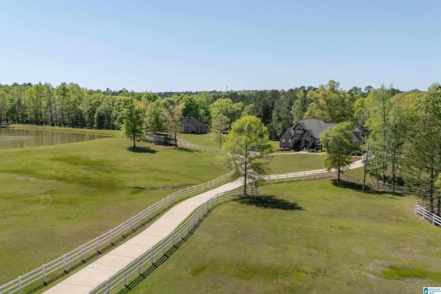 view of property's community with a rural view, a yard, a water view, and fence