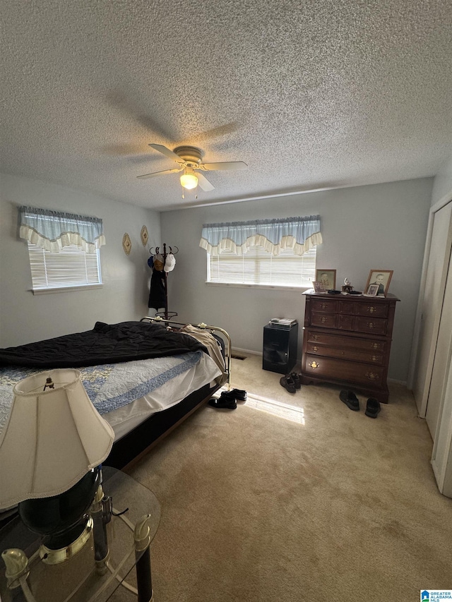 carpeted bedroom with multiple windows, a ceiling fan, and a textured ceiling
