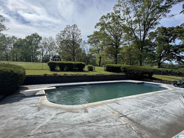 outdoor pool with a patio and a lawn