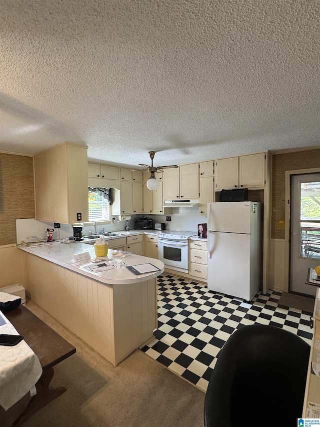 kitchen with a sink, light countertops, white appliances, a peninsula, and light floors