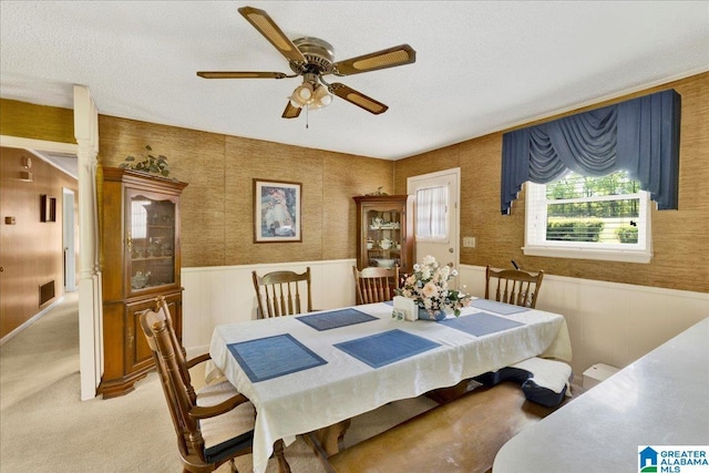 dining space featuring wainscoting, a ceiling fan, visible vents, and light colored carpet