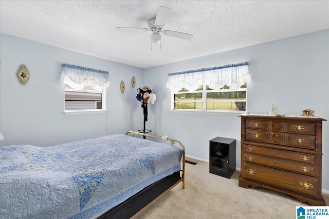 bedroom featuring ceiling fan, light carpet, a textured ceiling, and baseboards