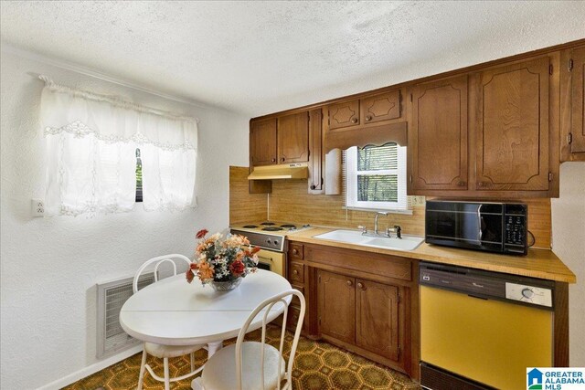 kitchen featuring a sink, tasteful backsplash, black microwave, dishwasher, and under cabinet range hood