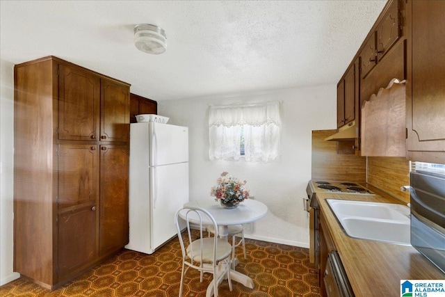 kitchen featuring dark floors, range with electric stovetop, under cabinet range hood, dishwasher, and freestanding refrigerator