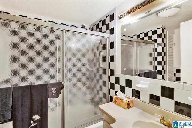 full bath with wallpapered walls, tile walls, a textured ceiling, and vanity