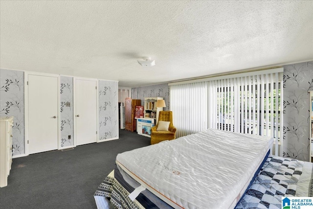 bedroom with wallpapered walls, carpet, and a textured ceiling