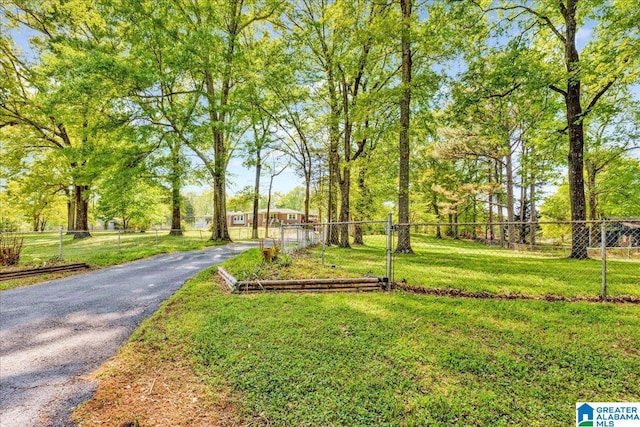 view of property's community with a lawn, fence, and aphalt driveway