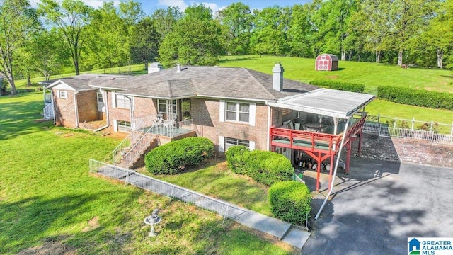 rear view of property featuring stairway, fence, a shed, an outdoor structure, and a lawn