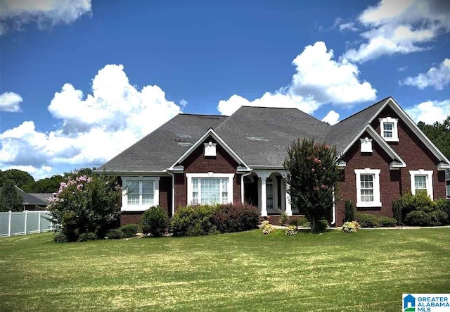 craftsman inspired home with brick siding, fence, and a front yard