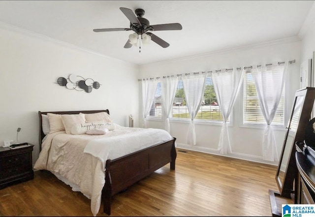 bedroom with baseboards, ornamental molding, ceiling fan, and wood finished floors