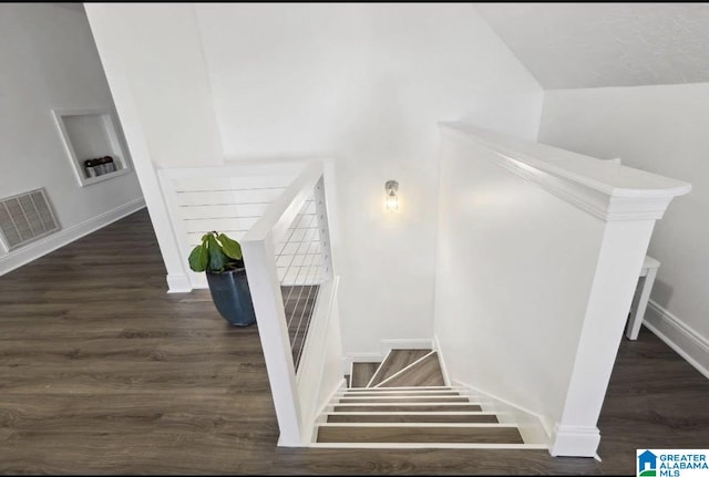 staircase featuring baseboards, visible vents, and wood finished floors